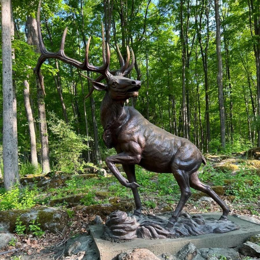 A magnificent bronze elk sculpture standing in a garden