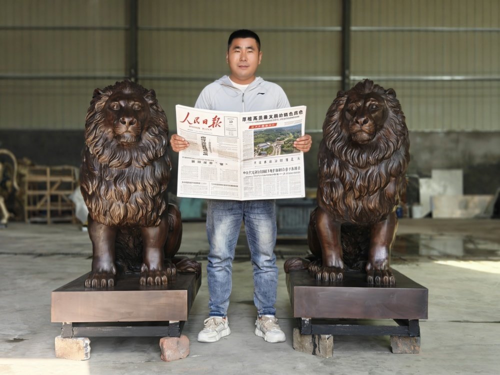 A finished bronze lion statue with a newspaper for date verification before shipping.