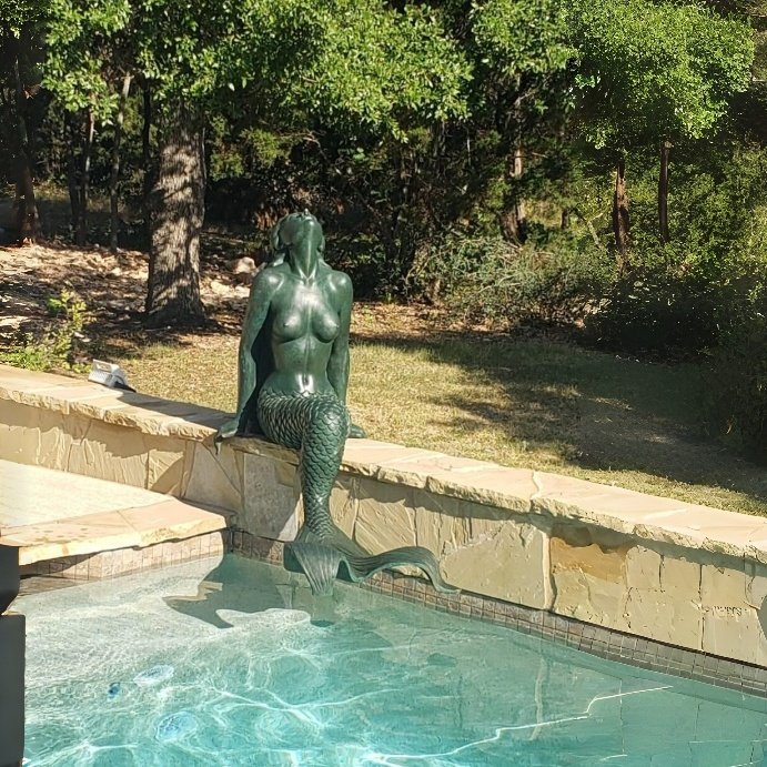 Verdigris bronze mermaid sculpture installed beside a swimming pool in the USA